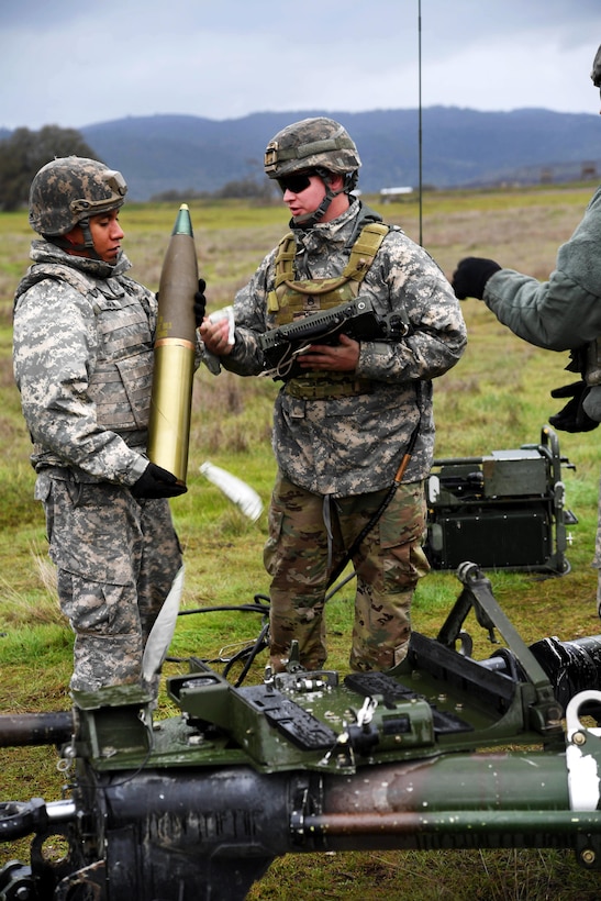 Army Staff Sgt. Jesse Gould, right, inspects a 105mm round before test firing an M119A3 105mm howitzer system at Camp Roberts, Calif., Jan. 18, 2017. Gould is a gunnery section chief assigned to Alpha and Bravo Battery, 1st Battalion, 143rd Field Artillery Regiment. Navy photo by Petty Officer 2nd Class Timothy M. Black