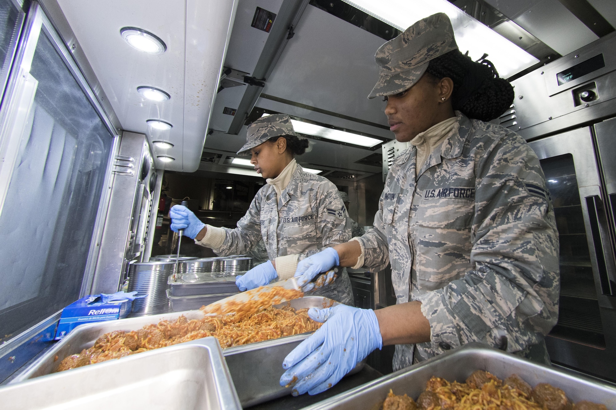 U.S. Air Force Airman 1st Class Ambrasia Washington, right, and Kayla Akers from the 116th Air Control Wing (ACW) Services Flight, Georgia Air National Guard (ANG), prepare trays of spaghetti during dinner preparation for joint-forces personnel supporting the 58th Presidential Inauguration, Washington, D.C., January 18, 2017. A team of 10 Airmen from the 116th ACW deployed with their Disaster Relief Mobile Kitchen Trailer (DRMKT).  Working from FedEx Field, home to the Washington Redskins, the team worked along side services teams from other ANG units across the nation preparing and serving meals to about 3,500 joint-force members per day deployed to the National Capital Region. In all, about 7,500 National Guard Soldiers and Airmen, from 44 states, three territories and the District of Columbia, served with the specially created Joint Task Force – District of Columbia. As a whole, National Guard Soldiers and Airmen augmented the U.S. Secret Service, U.S. Capitol Police and D.C. Metropolitan Police forces on a range of support including traffic control, crowd management, logistics and communication. (U.S. Air National Guard photo by Senior Master Sgt. Roger Parsons)