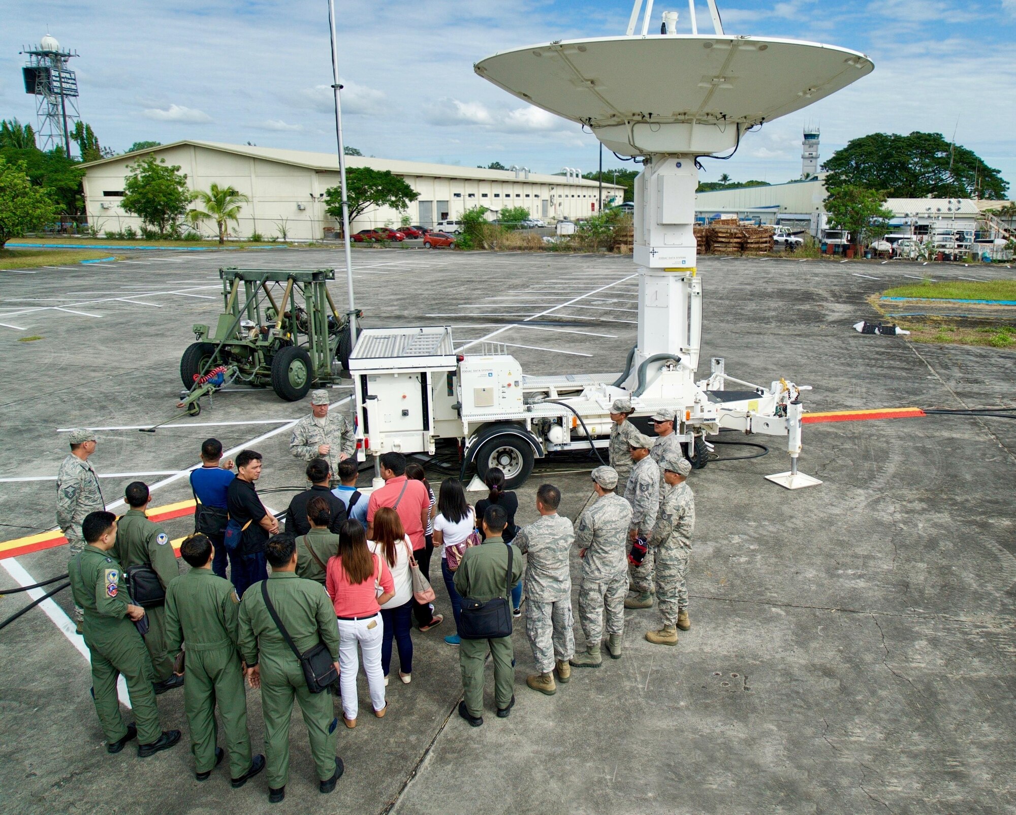 A combined group of Philippines Air Force and U.S. Air Force members gather around an Eagle Vision ground-satellite antenna during a worksite tour, Clark Air Base, Philippines, Jan. 16, 2017. Throughout the Subject Matter Expert Exchange (SMEE) military members from both nations will exchange ideas and experiences on how the Eagle Vision and the use of satellite imagery to enhance their combined Humanitarian Assistance and Disaster Relief capabilities. (U.S. Air Force photo by Tech. Sgt. James Stewart/Released)