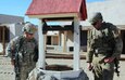 Delta Company first sergeant, Sgt. 1st Class Vincent Johnson (left) examines a well in the mock village for safety purposes. Sgt. Ian Pritchard (right) takes notes.