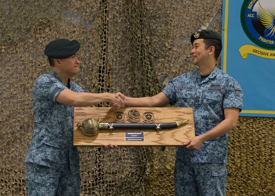 Republic of Singapore Air Force Senior Lt. Col. Tham Yeow Min passes a sword and the position of senior-ranking officer to Lt. Col. Oon Kok Choon, during a change of assignment ceremony at Mountain Home Air Force Base, Idaho, Jan. 17, 2017. Tham has been the SRO and Peace Carvin V Detachment Commander since June 2013. (U.S. Air Force photo by Airman 1st Class Chester Mientkiewicz/Released)