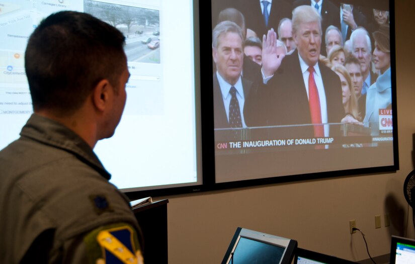 Lt. Col. David Fink, 11th Wing command post director, watches a live broadcast from Joint Base Andrews, Md., Jan. 20, 2017, of president elect Donald Trump taking the oath of office. Fink and approximately 20 other representatives from Team Andrews formed a crisis action team to monitor and coordinate Air Force personnel participating in the presidential inauguration ceremony and parade. (U.S. Air Force photo by Staff Sgt. Joe Yanik)