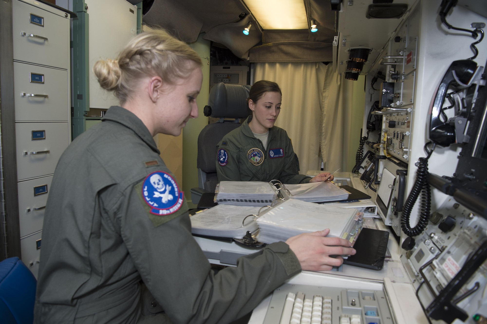 First Lt. Ashley Mirsky, 319th Missile Squadron missile combat crew commander, and 2nd Lt. Marie Blair, 319th MS deputy missile combat crew commander, run through a checklist in a launch control center in the 90th Missile Wing missile complex, Dec. 19, 2016. The crew has been paired together for four months and continuously challenges each other on their weapons system knowledge. (U.S. Air Force photo by 1st Lt. Veronica Perez)