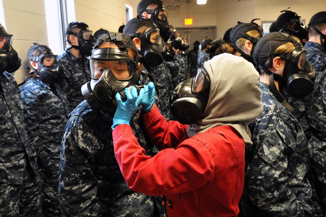 A firefighting instructor helps a recruit properly seal her gas mask in a Recruit Training Command confidence chamber at Naval Station Great Lakes, Ill., Jan. 18, 2017. Recruits attend a week of firefighting training to gain basic knowledge and confidence in the Navy's firefighting equipment. Navy photo by Chief Petty Officer Seth Schaeffer