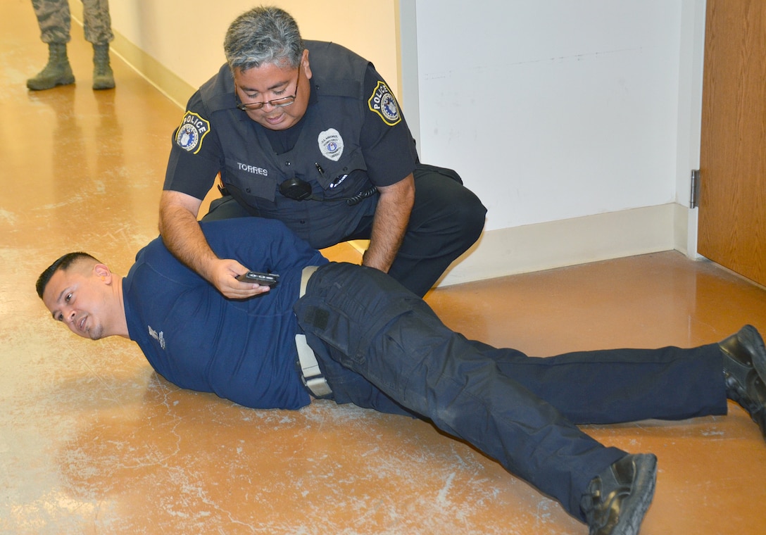 Officer David Torres with the 502nd Security Forces Squadron apprehends a suspected armed intruder, played by. William Torres, a training instructor with Security Forces Squadron, in Smith Hall on the Medical Education and Training Campus, or METC, at Joint Base San Antonio-Fort Sam Houston Jan. 18. METC worked with the security response team from the 502nd Air Base Wing to conduct an active shooter/lockdown drill.