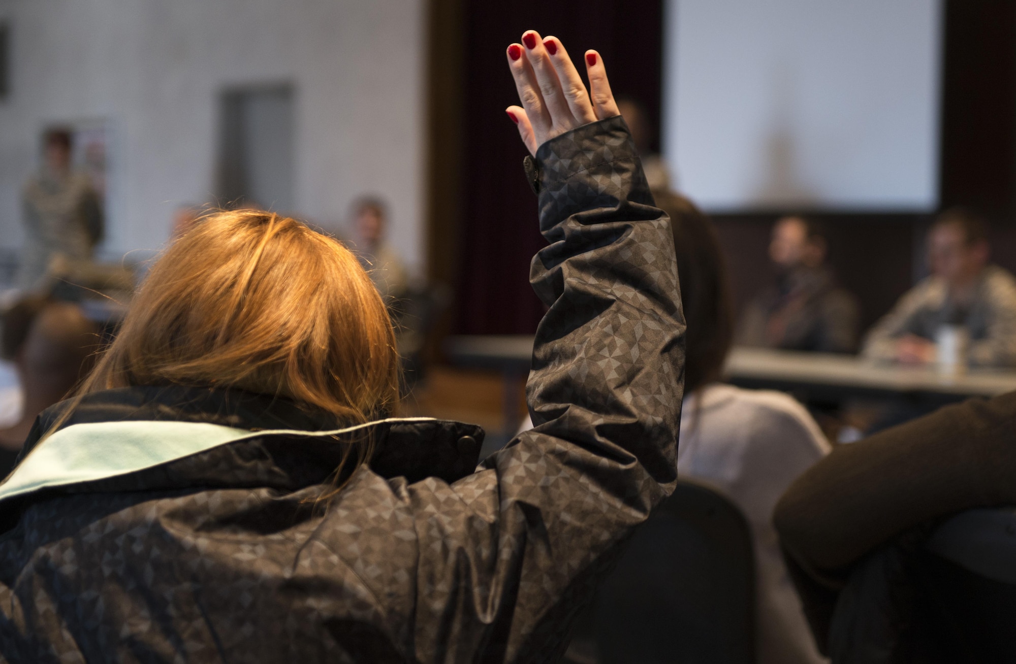 A participant raises her hand to ask a question during a Noncombatant Evacuation Operation Townhall meeting Jan. 23, 2017, at Yokota Air Base, Japan. NEO could occur under a variety of circumstances, including civil unrest, military uprisings, environmental concerns, and natural disasters. (U.S. Air Force Photo by Airman 1st Class Juan Torres)