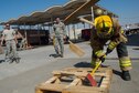 A 380th Expeditionary Civil Engineering Squadron firefighter smashes a wooden pallet during a timed firefighter confidence course at an undisclosed location in Southwest Asia, Jan. 16, 2016. Wearing up to 75 pounds of equipment, participants completed nine stages during the course including a ladder climb, hose drag, sled pull, hose throw, equipment carry, forcible entry, hotel pack, equipment hoisting and rescue. (U.S. Air Force photo/Senior Airman Tyler Woodward)