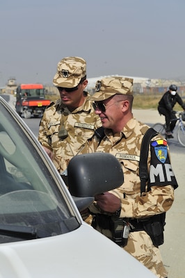 First Sgt. (Plutonier-major) Victor Balan and Cpl. (Caporal) Marius Toma conducted a policy compliance checkpoint on Bagram Airfield.  The checks are randomly conducted at various locations to check the identity of the driver and occupants as well as check the vehicle safety features functionality and the vehicle registration. The checks are routine requirements for a typical Provost Marshall military police patrol.  Balan and Toma  are members of the 4th Romanian Military Police Detachment from the Romanian Land Forces 265th MP Battalion, in Bucharest.
