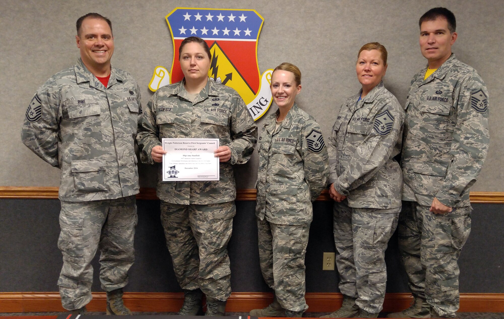 Staff Sgt. Amy Stanfield, 445th Operations Support Squadron, is presented the December 2016 Diamond Sharp award by Jan. 21, 2017. 445th Airlift Wing first sergeants Senior Master Sgt. Eric Rine, 445th Aerospace Medicine Squadron, Master Sgt. Sierra Cabungcal, 445th OSS, Senior Master Sgt. Glenda Marck, 89th Airlift Squadron, and Master Sgt. David Reagan, 445th Aeromedical Evacuation Squadron, presented her with the award for exemplary performance and adherence to the Air Force Core Values, attitude and appearance. (Courtesy photo) 