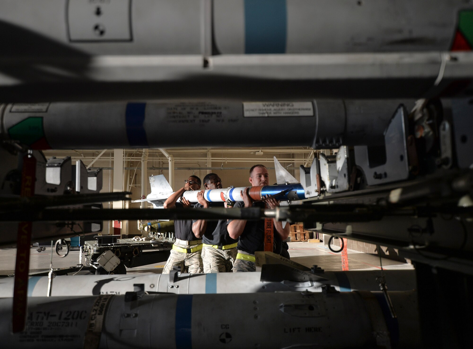 U.S. Air Force Staff Sgt. Christopher A. Holmes, Senior Airman Michael B. Cheek and Airman 1st Class Elijah Cruz, 43rd Aircraft Maintenance Unit aircraft armament systems technicians remove a training missile from a holding platform to manually load into an F-22 Raptor at Tyndall Air Force Base, Fla., Jan. 20, 2017. The load crew was the first of four teams to compete for the 2016 Load Crew of the Year Award. (U.S. Air Force photo by Tech. Sgt. Javier Cruz/Released)