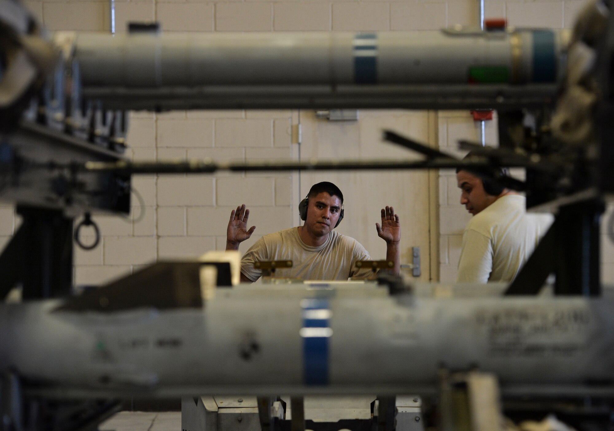 U.S. Air Force Staff Sgt. Michael A. Avalos, 95th Aircraft Maintenance Unit armament systems technician, raises his hands from the steering wheel of a munitions transportation vehicle to allow Staff Sgt. Vincent A. Miller, 95th Aircraft Maintenance Unit armament systems technician, to make adjustments to a loading arm at Tyndall Air Force Base, Fla., Jan. 20, 2017. The Airmen were evaluated on their ability to load weapon systems into an F-22 Raptor in a timely, safe and reliable manner under 90 minutes. (U.S. Air Force photo by Tech. Sgt. Javier Cruz/Released)