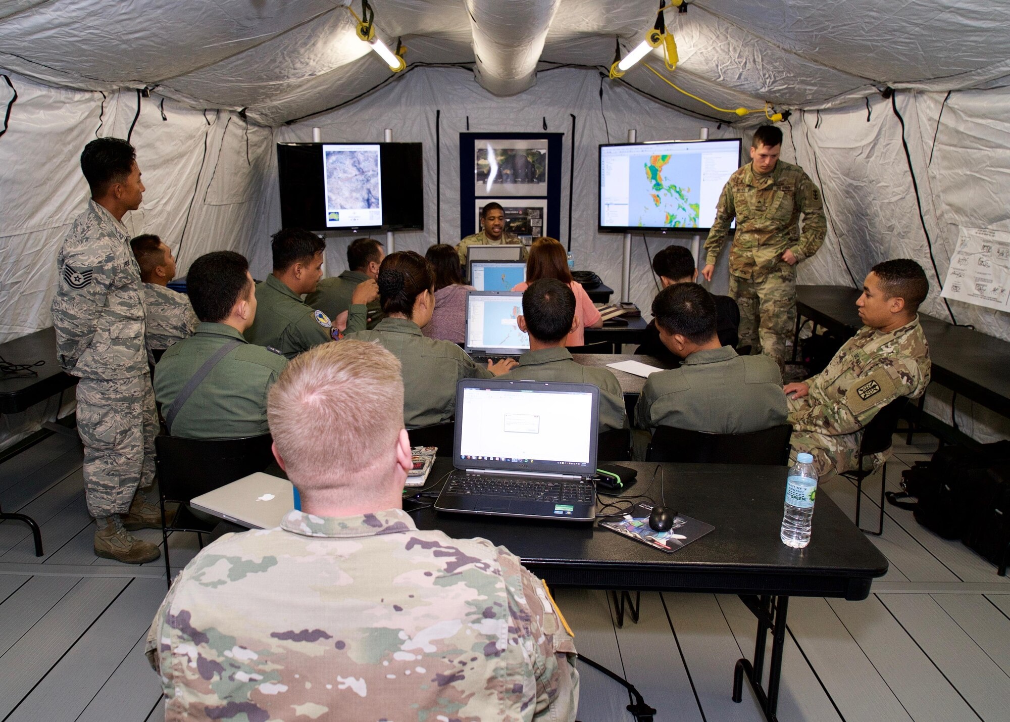 A combined group of Philippine and U.S. service members follow Spc. Antonio Martin, a geospatial engineer with the U.S. Army's 5th Engineer Detachment Geospatial Planning Cell, while he demonstrates techniques for layering map products, Clark Air Base, Philippines, Jan. 20, 2017. The group is participating in a two-week long Subject Matter Expert Exchange (SMEE). Throughout the SMEE military members from both nations will train together using satellite imagery to enhance their combined readiness when conducting Humanitarian Assistance and Disaster Relief operaions common in the Asia-Pacific. (U.S. Air Force photo by Tech. Sgt. James Stewart/Released)