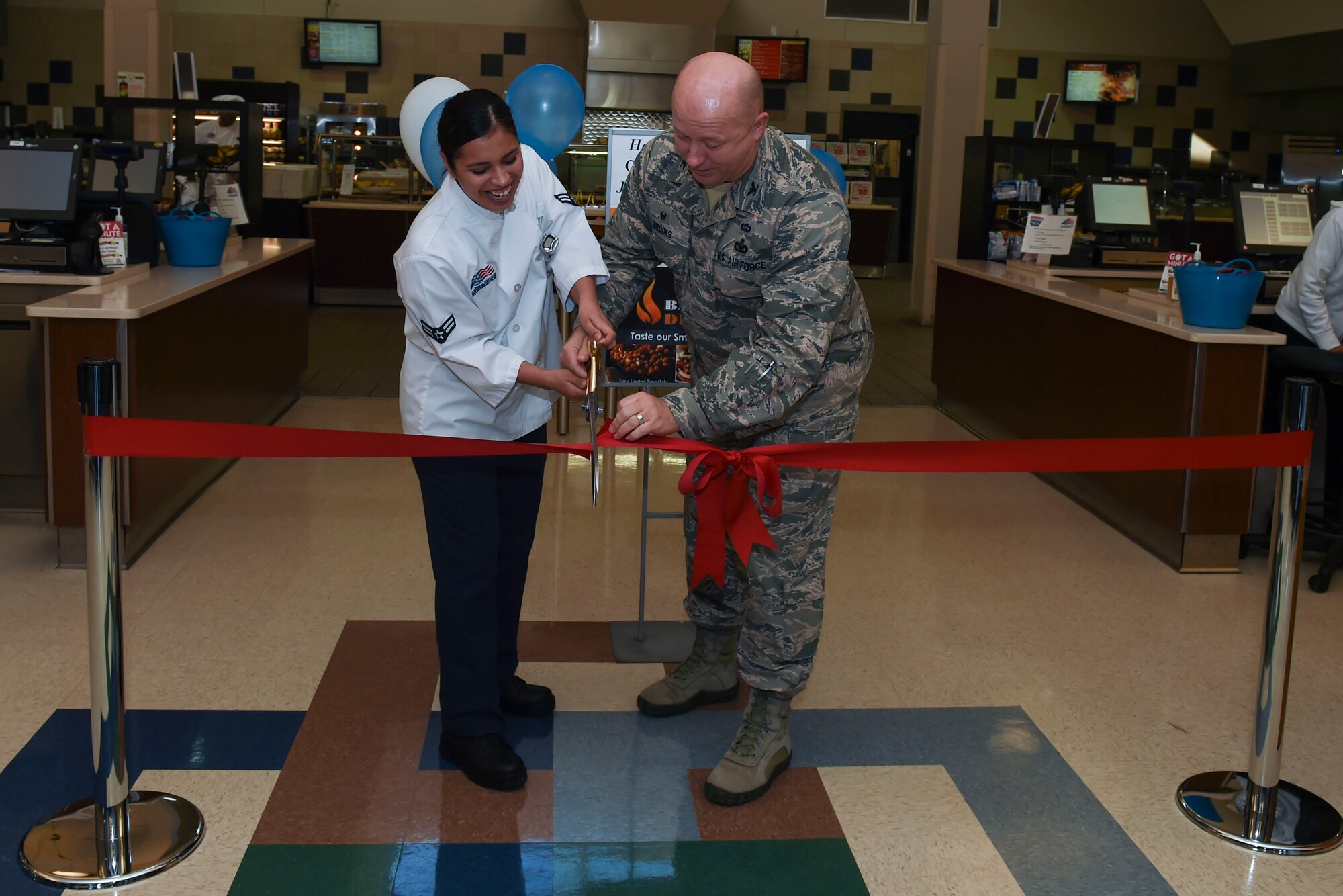 U.S. Air Force Col. William Brooks, 19th Mission Support Group commander, and Airman 1st Class Grethel Rodgers, 19th Force Support Squadron services apprentice, cut the grand re-opening ceremony ribbon Jan. 23, 2017, at the Hercules Dining Facility on Little Rock Air Force Base, Ark. The Hercules Dining Facility upgraded three sections to include the deli, pizza zone and grill. (U.S. Air Force photo by Staff Sgt. Kaylee Clark) 