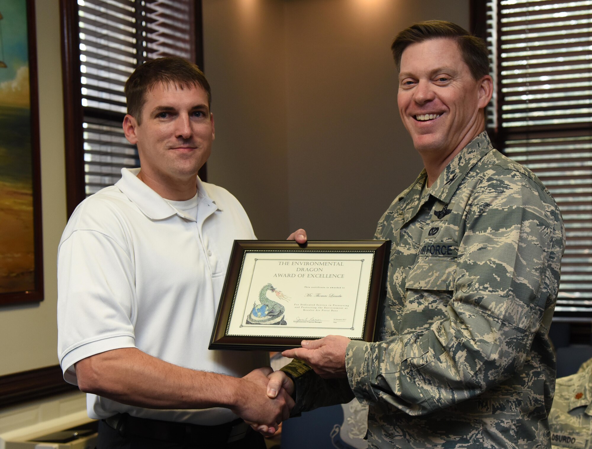 Col. C. Mike Smith, 81st Training Wing vice commander, presents Thomas Lassabe, 81st Training Support Squadron training technician chief, the Environmental Dragon Award during the Energy Environmental Safety and Occupational Health Council Meeting at the 81st TRW headquarters building Jan. 18, 2017, on Keesler Air Force Base, Miss. Lassabe received the award for being a positive performer during the October 2016 Unit Effectiveness Inspection and for his commitment to the goals of the Keesler Environmental Management System. The Dragon Award is given by the base environmental office in recognition of outstanding performers. (U.S. Air Force photo by Kemberly Groue)
