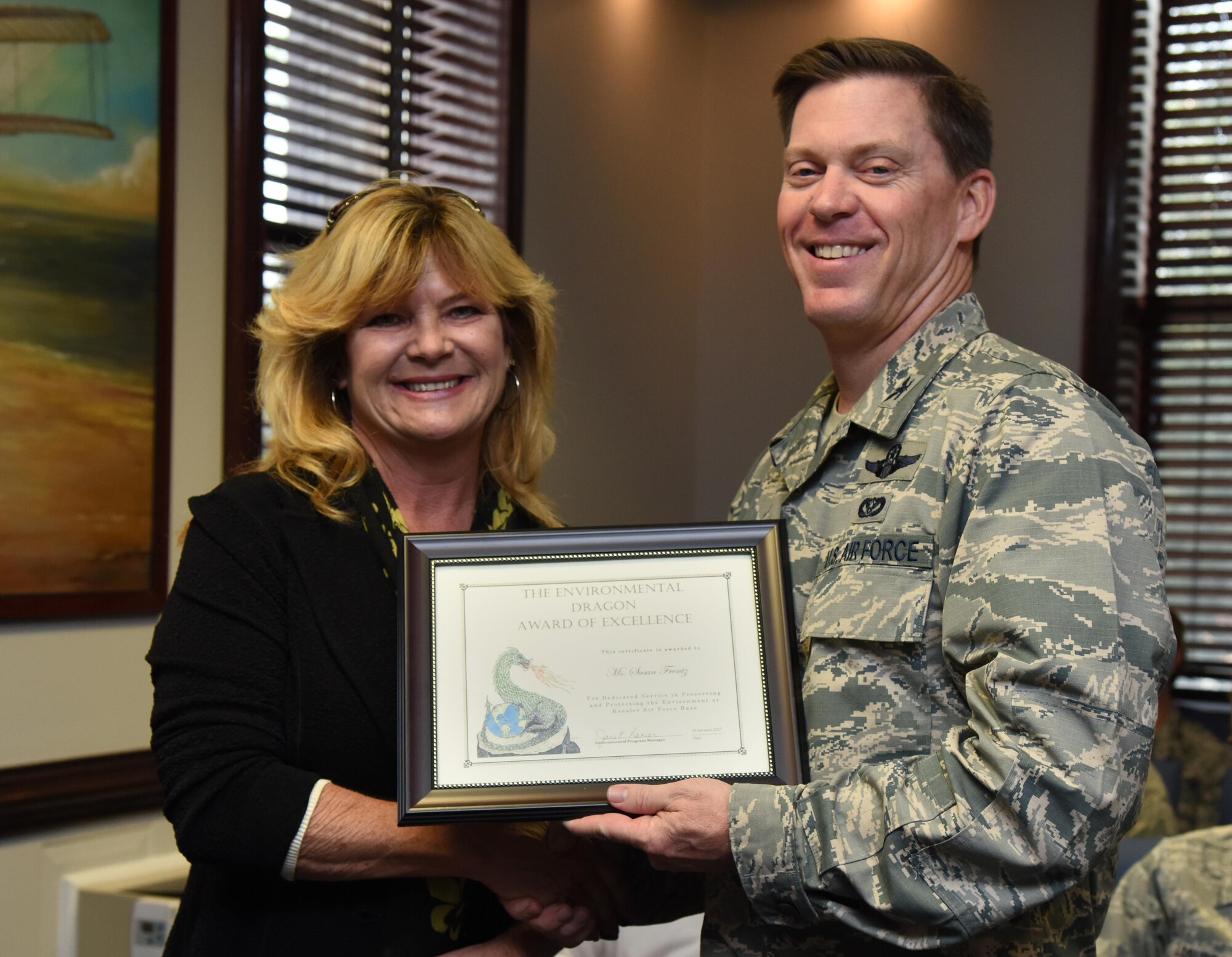 Col. C. Mike Smith, 81st Training Wing vice commander, presents Susan Frentz, Base Operations Support structure shop painter, the Environmental Dragon Award during the Energy Environmental Safety and Occupational Health Council Meeting at the 81st TRW headquarters building Jan. 18, 2017, on Keesler Air Force Base, Miss. Frentz received the award for managing an excellent hazardous materials program and for identifying products that will meet application and performance requirements while also being more eco-friendly. The Dragon Award is given by the base environmental office in recognition of outstanding performers. (U.S. Air Force photo by Kemberly Groue)