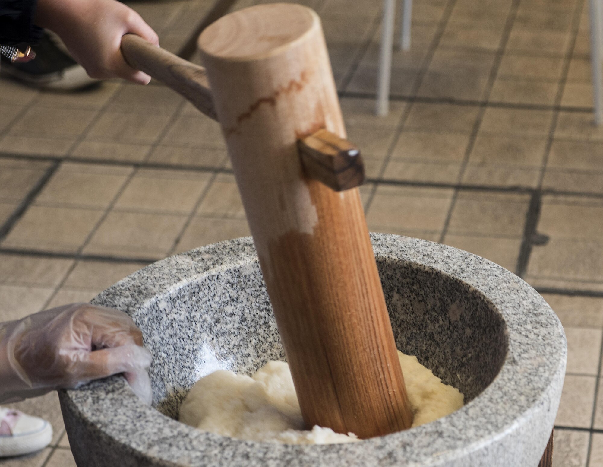 A wooden mallet, called a Kine, pounds rice into a mash called mochi Jan. 21, 2017, at Koza Music City, Okinawa, Japan. Making mochi requires at least two people, one person to pound the rice and another to roll and wet it so it to the right consistency. (U.S. Air Force photo by Airman 1st Class Corey Pettis/Released)
