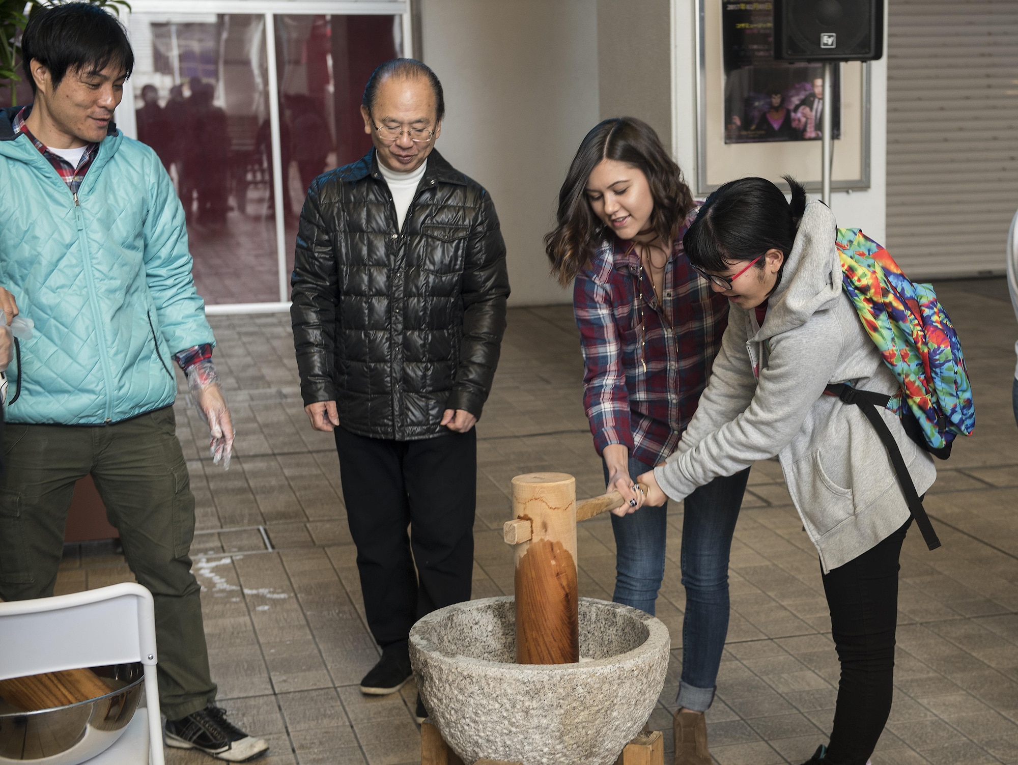 Members of the Kadena Teen Center and Okinawa City junior high school use a wooden mallet to pound rice to make mochi Jan. 21, 2017, at Koza Music City, Okinawa, Japan. The Let’s Learn English exchange builds relationships between Okinawan and American teenagers. (U.S. Air Force photo by Airman 1st Class Corey Pettis/Released) 
