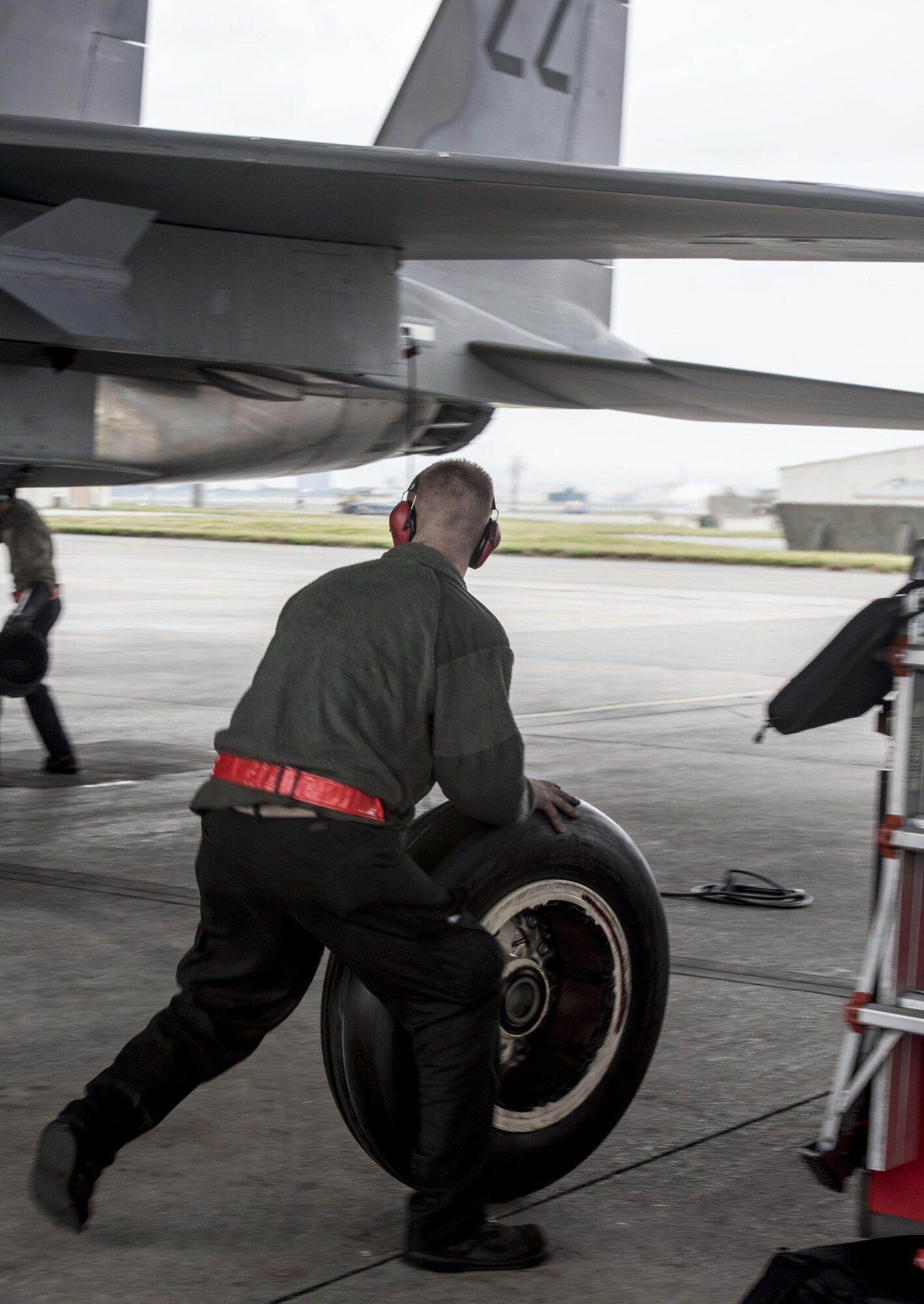 U.S. Air Force Senior Airman Jeffrey Baccus, 67th Aircraft Maintenance Unit crew chief, rolls in a replacement tire for an F-15 Eagle Jan 10, 2017, at Kadena Air Base, Japan. With an experienced crew, it can take less than 15 minutes to completely change a tire on the multi-million dollar aircraft. (U.S. Air Force photo by Senior Airman Omari Bernard/Released)