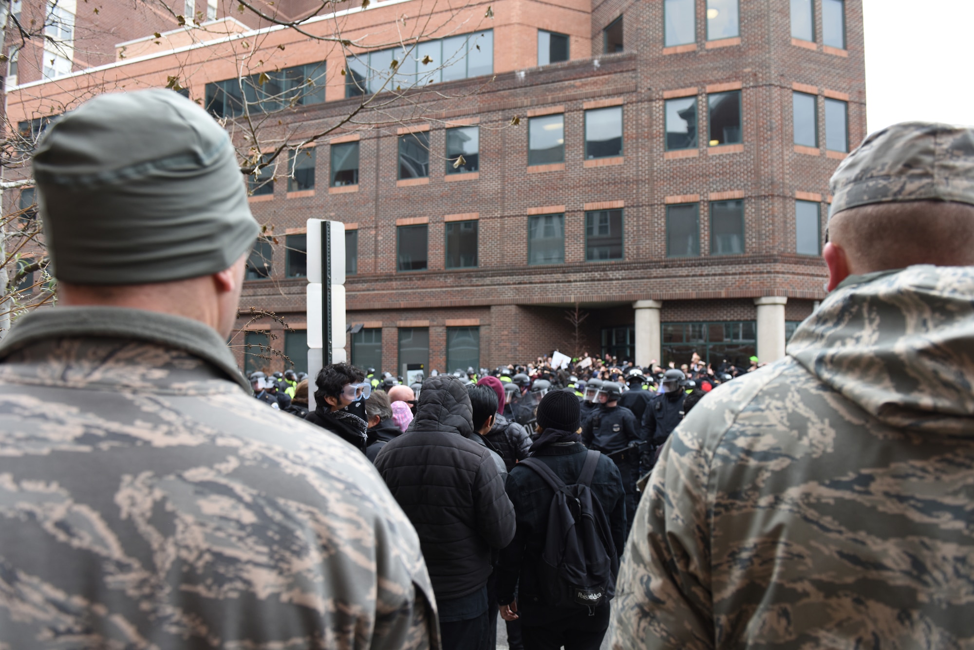 Pennsylvania Air National Guardsmen man a traffic control point in Washington, D.C., Jan. 20, 2017, while protesters are detained by police after hurling rocks, metal debris and a hammer toward law enforcement officials. More than 1,000 PANG Soldiers and Airmen headed to D.C. to support a safe, secure inauguration. They joined more than 7,000 Guardsmen from 44 states. (U.S. Air National Guard photo by 2nd Lt. Susan Penning/Released) 