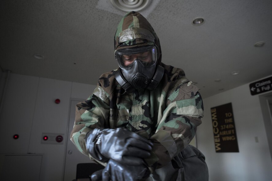 Staff Sgt. David Owsanka, 374th Airlift Wing public affairs photojournalist, dons  Mission-Oriented Protective Posture gear during a Samurai Readiness Training Day at Yokota Air Base, Japan, Jan. 23, 2017. Airmen must quickly and correctly don MOPP gear. (U.S. Air Force photo by Yasuo Osakabe)