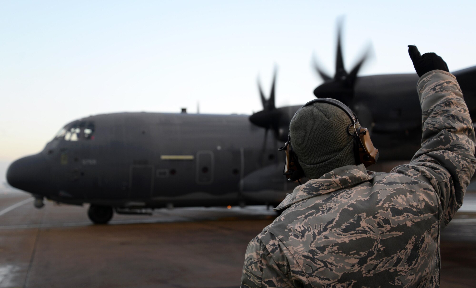 A U.S. Air Force crewchief, assigned to the 352d Special Operations Aircraft Maintenance Squadron, gives a thumbs up to an MC-130J Commando II from the 67th Special Operations Squdron Jan. 17, 2016, as it taxis on the flight line on RAF Mildenhall, England. Prior to takeoff the aircraft underwent de-icing procedures to ensure free movement of the primary and secondary flight controls. (U.S. Air Force photo by Senior Airman Justine Rho)