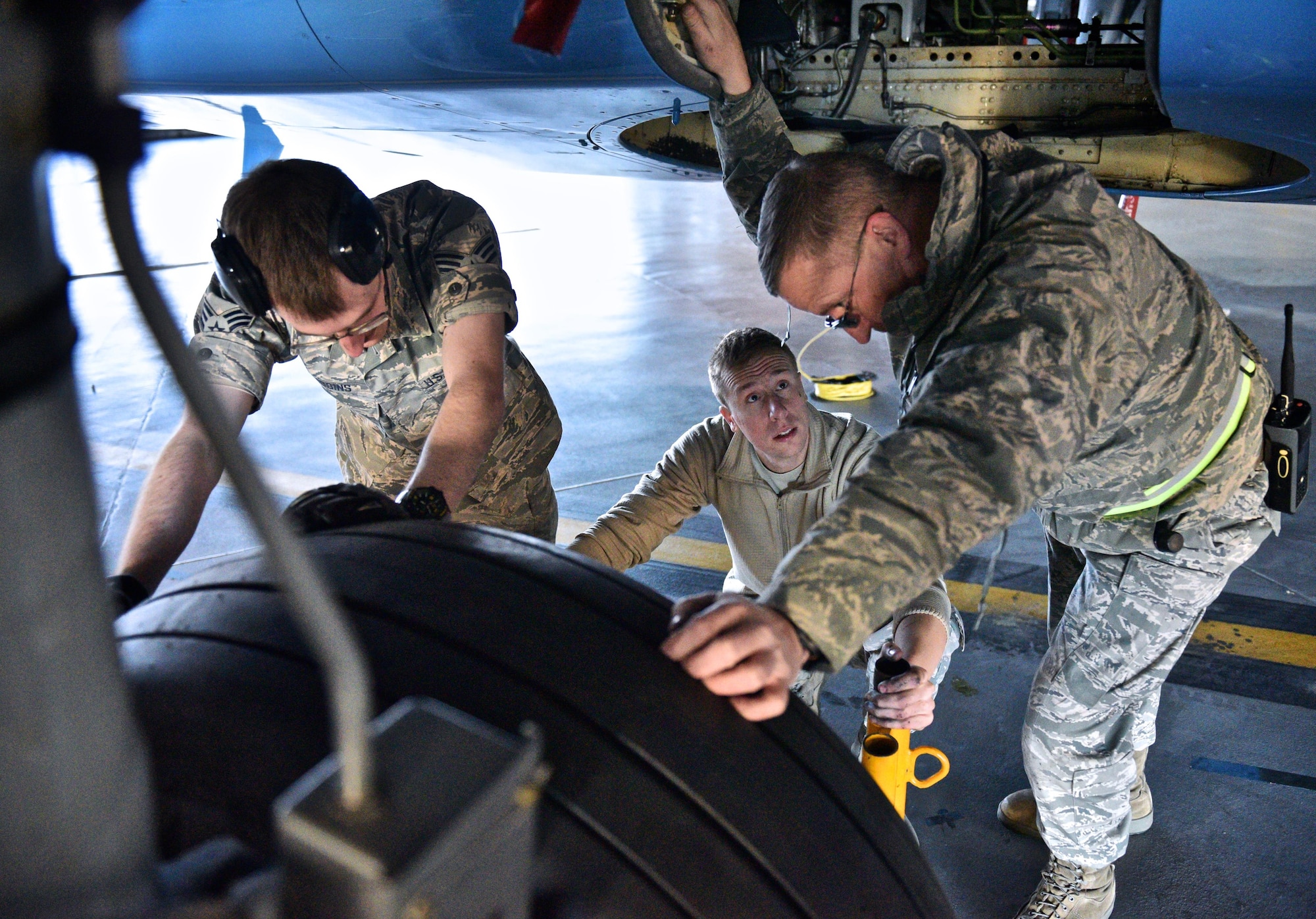 Staff Sgt. Damien Ford, center,  seeks guidance from fellow 932nd Maintenance Squadron C-40 maintainer Master Sgt. Keith Winter, right, and Senior Airman Anthony Gribbins, left, during a routine tire change Dec. 29, 2016 at Scott Air Force Base, Illinois.  Worn tires get swapped out weekly on any one of the four C-40 aircraft maintained by the 932nd MXS.  (U.S. Air Force photo by Christopher Parr)