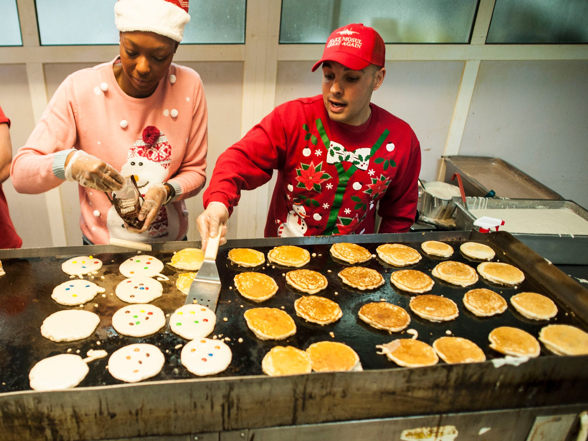 Company grade officer council members cook pancakes at the dining facility Dec. 25, 2016, at an undisclosed location in Southwest Asia.  The CGOC provided pancakes and toppings to Airmen and soldiers Christmas morning. (U.S. Air Force photo by Staff Sgt. Eboni Reams)
