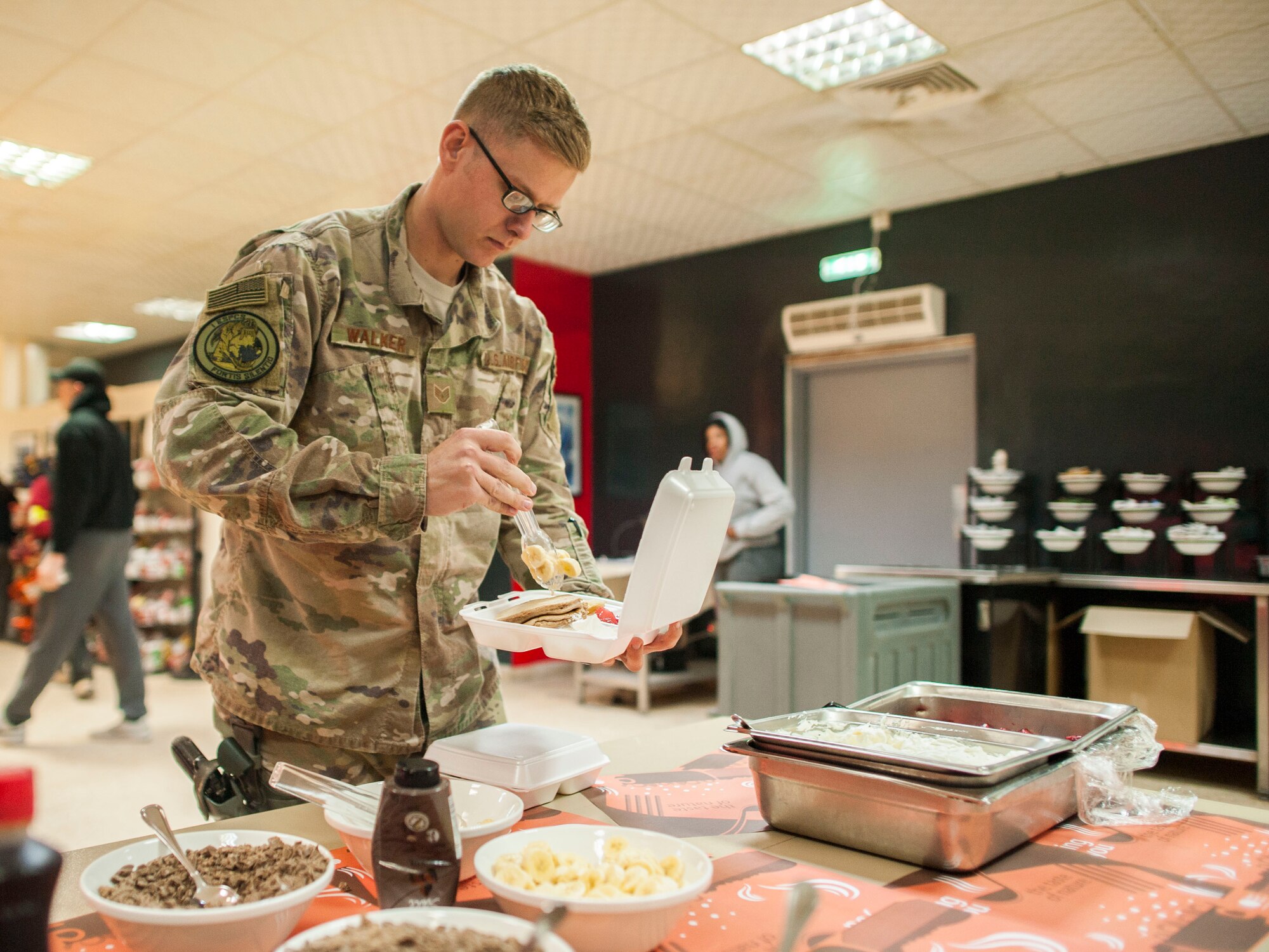 An Airman assigned to the 332nd Expeditionary Security Forces Squadron puts toppings on his pancakes Dec. 25, 2016, at an undisclosed location in Southwest Asia. The company grade officer council served Christmas Day breakfast to the soldiers and Airmen. (U.S. Air Force photo by Staff Sgt. Eboni Reams) 