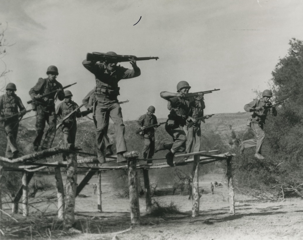 These United States Marine Raiders dash at full speed along narrow poles.  It's part  of their training at Camp Pendleton, California to make them the finest combat organization in the world. (January 1943)