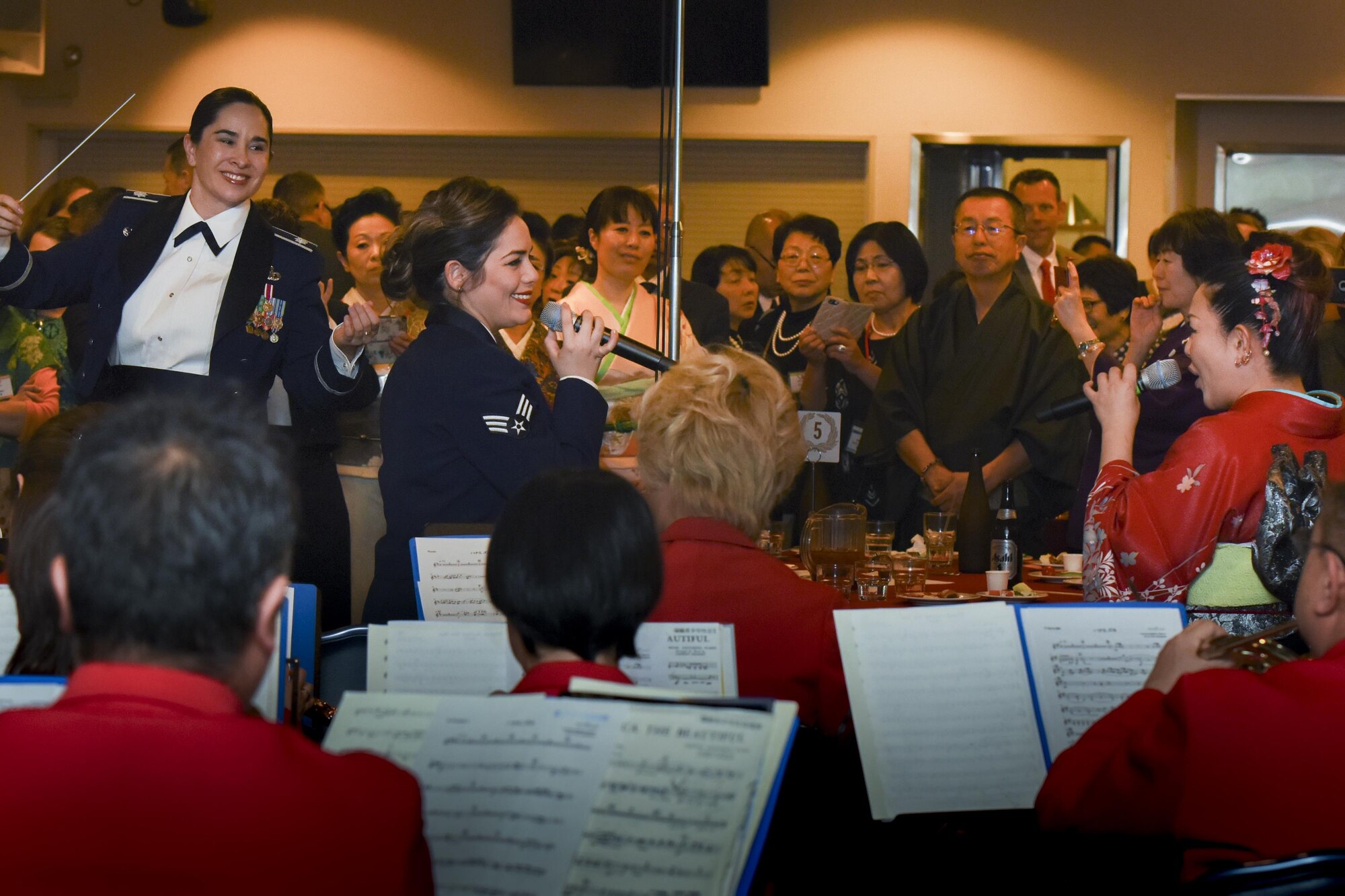 (Left to right) Senior Airmen Maritzaida Amador, Band of the Pacific-Asia vocalist, and Miki Takahashi, a member of the Mizuho-Yokota Friendship Association sing together during the Joint New Year’s Party at Yokota Air Base, Japan, Jan. 21, 2017. The Band of the Pacific-Asia collaborated with Mizuho Youth Brass Band. (U.S. Air Force photo by Machiko Arita)