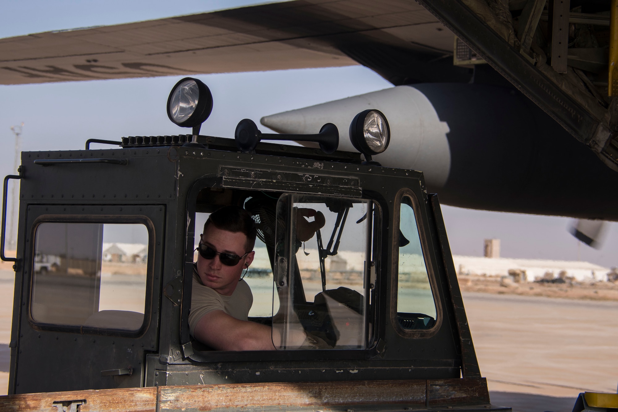 Senior Airman Christian Hall, an 870th Air Expeditionary Squadron aerial porter, watches as a pallet of supplies is offloaded from the K-loader he is driving at Al Asad Air Base, Iraq, Jan. 9, 2017. 870th AEAS aerial porters are required to be able to operate a variety of vehicles and machinery around the aerial port. (U.S. Air Force photo/Senior Airman Andrew Park)