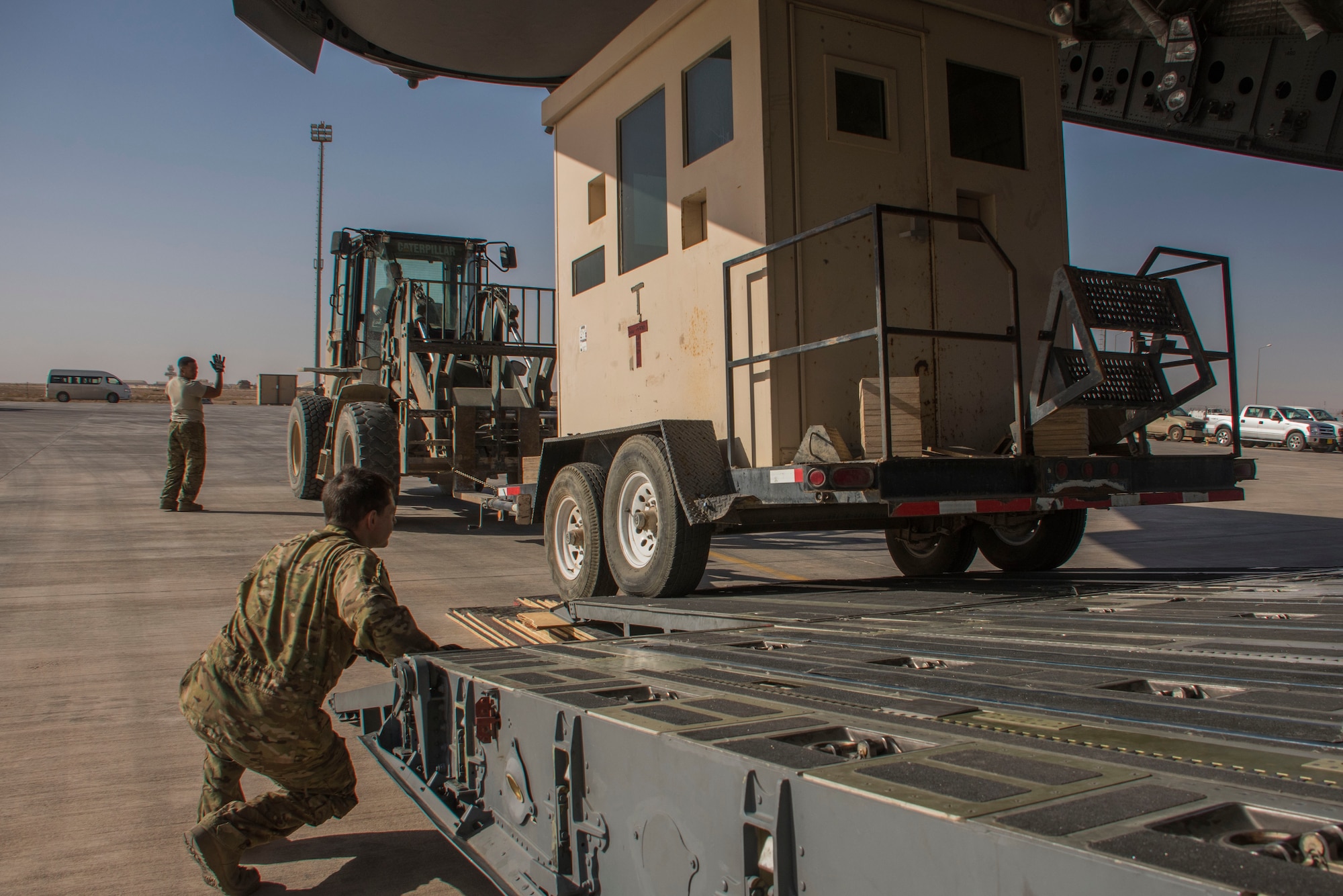 An aerial porter, left, and a loadmaster, right, work together to guide a forklift in towing a structure out of a C-17 Globemaster III at Al Asad Air Base, Iraq, Jan. 9, 2017. Loadmasters and aerial porters often work off each other’s expertise to efficiently onload and offload aircraft. (U.S. Air Force photo/Senior Airman Andrew Park)