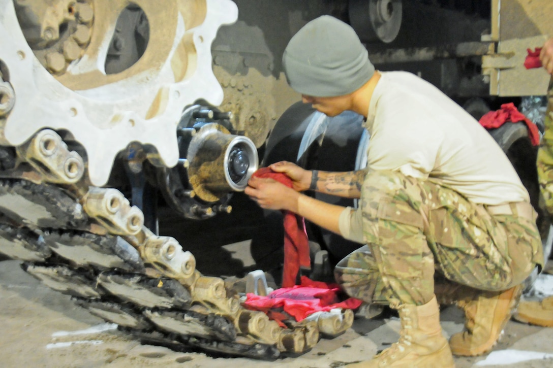 A soldier wipes grease off the tracks of an M1A2 Abrams tank during routine maintenance in Zagan, Poland, Jan. 24, 2017. The soldier is on a deployment supporting Operation Atlantic Resolve. Army photo by Staff Sgt. Corinna Baltos