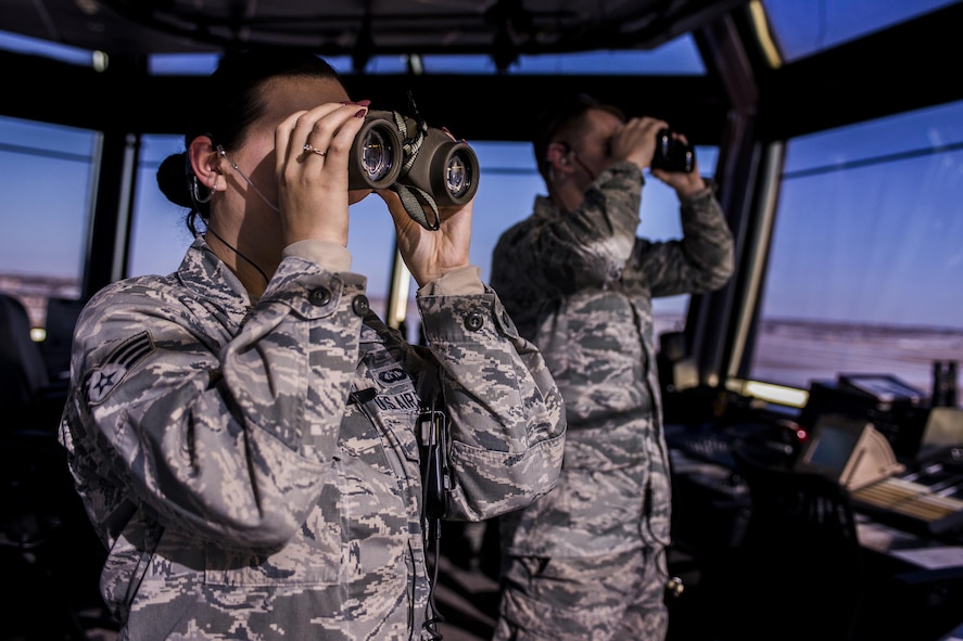 Two 27th Special Operations Support Squadron Air Traffic Controllers look through binoculars toward incoming aircraft Jan. 6, 2017, at Cannon Air Force Base, N.M. The controllers in the tower work directly with Radar Approach Control to ensure all aircraft launch, fly and arrive safely. (U.S. Air Force photo by Senior Airman Luke Kitterman/Released) 