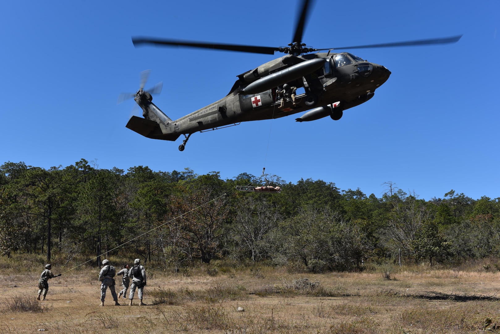 A team comprised of Joint Security Forces personnel and 1st Battalion, 228th Aviation regiment flight paramedics prepares to hoist a mannequin onto a helicopter during a joint Medical Evacuation training, near Soto Cano Air Base, Honduras, Jan. 18, 2017. The training exercise increased coordination between ground forces and flight crews to securely and safely perform an emergency medical evacuation in preparations for a real life event.