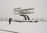 Snow blankets a sculpture of the Wright Flyer and the Wright Brothers Dec. 13, 2016, near a gate to Wright-Patterson Air Force Base, Ohio. The first significant snowfall of the season dumped four inches on the area, giving the landscape a sense of the holidays. (U.S. Air Force photo by R.J. Oriez/Released)