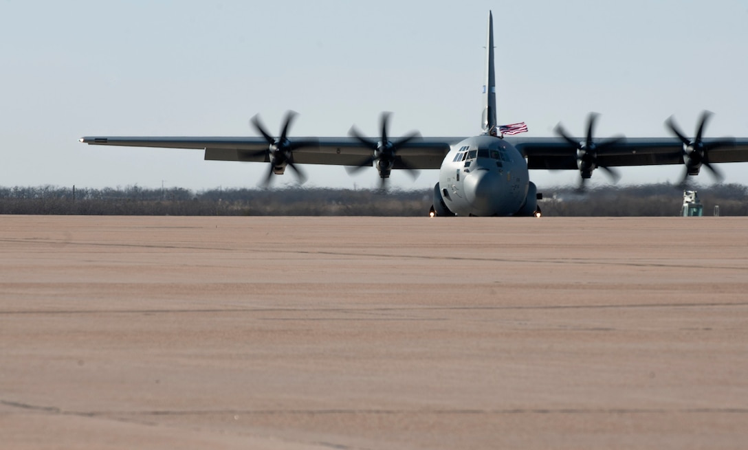 A U.S. Air Force Airman waves the American flag from a C-130J Super Hercules—signaling a safe return home—at Dyess Air Force Base, Texas, Jan. 20, 2016. The Airmen returned home after supporting the East African Response Force, logistics operations throughout the Horn of Africa and also Combined Joint Special Operations Task Force operations in Africa. 