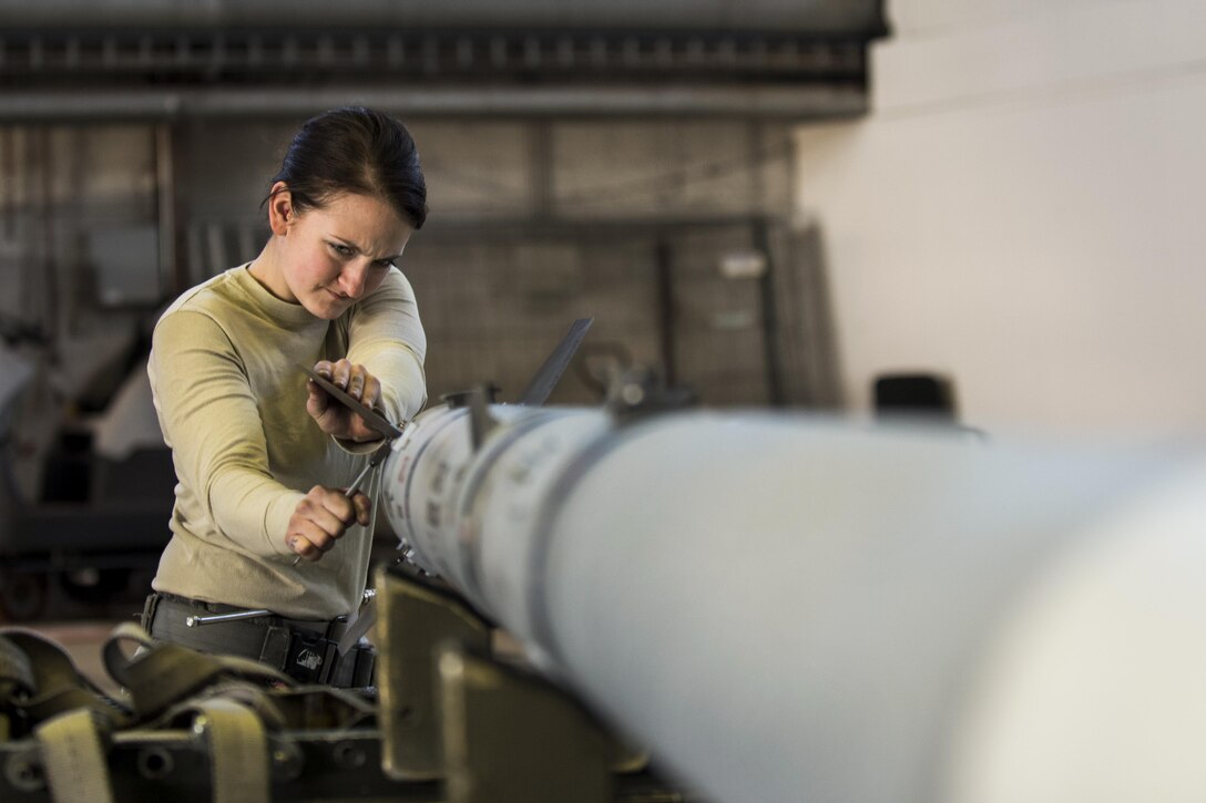 Air Force Airman 1st Class Gina Herringer-Koblack prepares an inert weapon during the annual weapons load competition at Spangdahlem Air Base, Germany, Jan. 20, 2016. During the event, two teams competed for the wing’s best load crew. Herringer-Koblack is a 52nd Aircraft Maintenance Squadron tactical aircraft weapons system specialist. Air Force photo by Airman 1st Class Preston Cherry