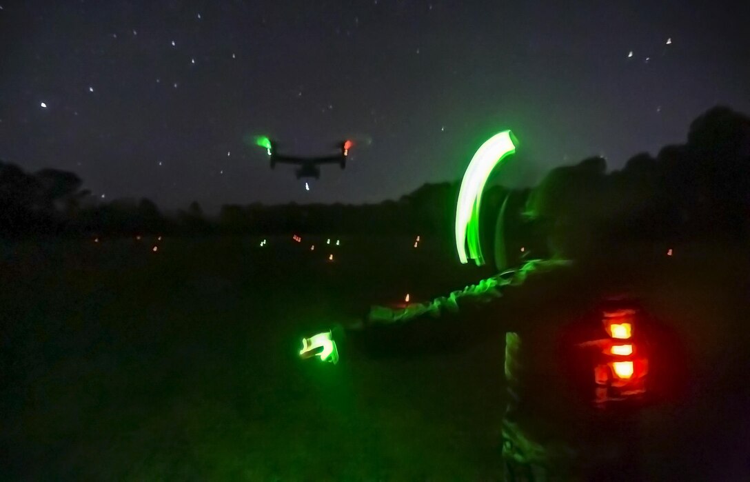 A Marine uses chemical light sticks to direct an MV-22B Osprey into a landing zone during an external lift exercise at Camp Lejeune, N.C., Jan. 24, 2017. An external lift provides a fast, effective way to move cargo and other heavy equipment, increasing the logistic capabilities of ground elements. The Marine is assigned to Combat Logistics Battalion 26. Marine Corps photo by Lance Cpl. Damarko Bones