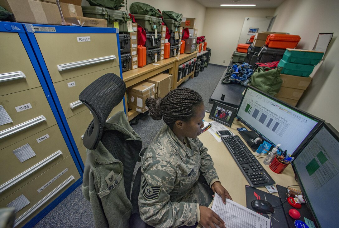 Tech Sgt. Shakuntala M. Willis, 374th Operations Support Squadron Aircrew Flight Equipment flight NCO in charge of the C-130J transition, works at her desk surrounded by the survival and life-support equipment she is in charge of Jan. 25, 2017, at Yokota Air Base, Japan. The AFE flight has been preparing aircrew survival and life-support equipment for the arrival of the new C-130J Super Hercules since May 2016. (U.S. Air Force photo by Airman 1st Class Donald Hudson)