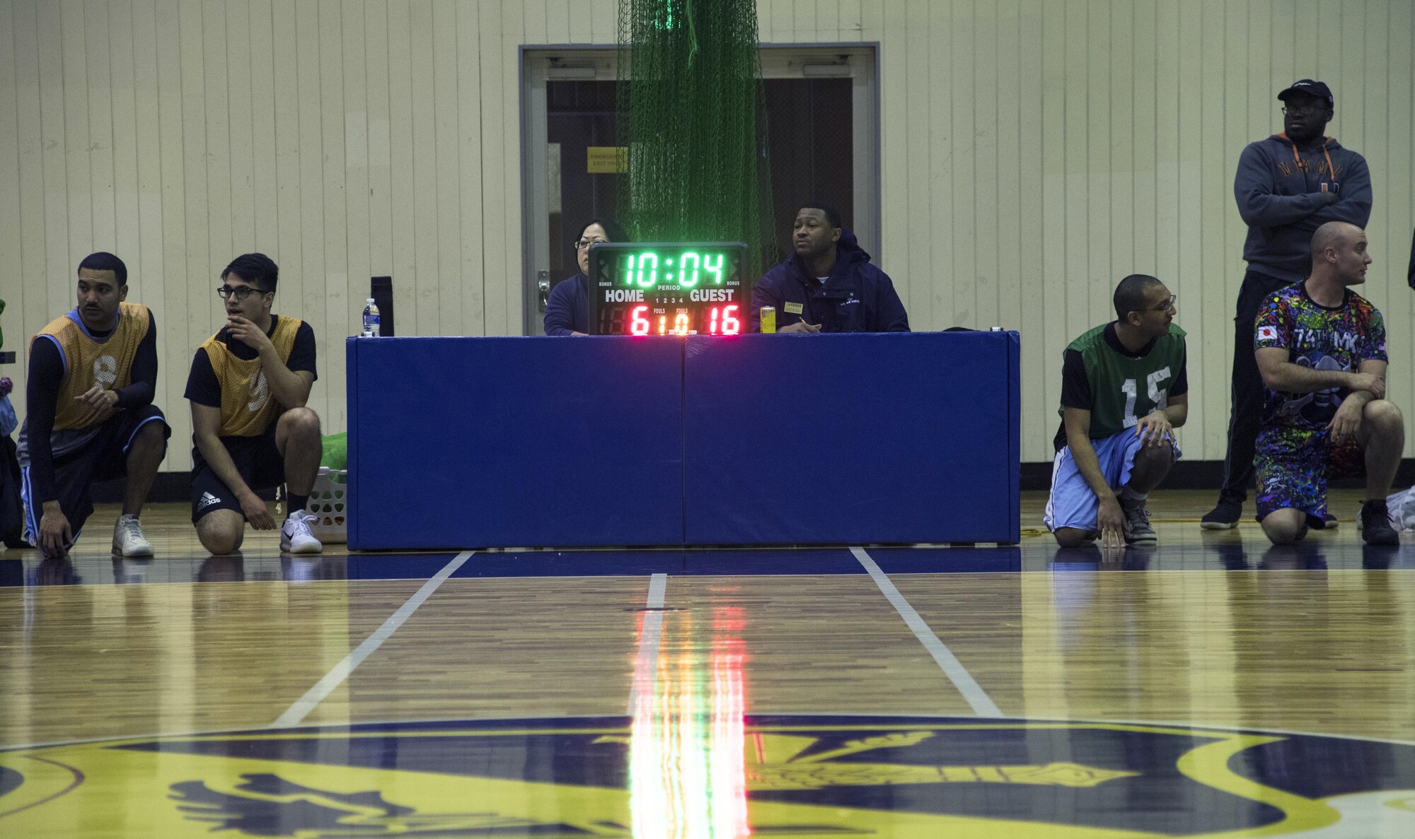 Players from both 374th Maintenance Squadron and 374th Communications Squadron teams wait to check in during the first half of the intramural basketball game at Yokota Air Base, Japan, Jan. 24, 2017. The 374 MXS team held a 26-19 lead at halftime. (U.S. Air Force photo by Staff Sgt. David Owsianka)