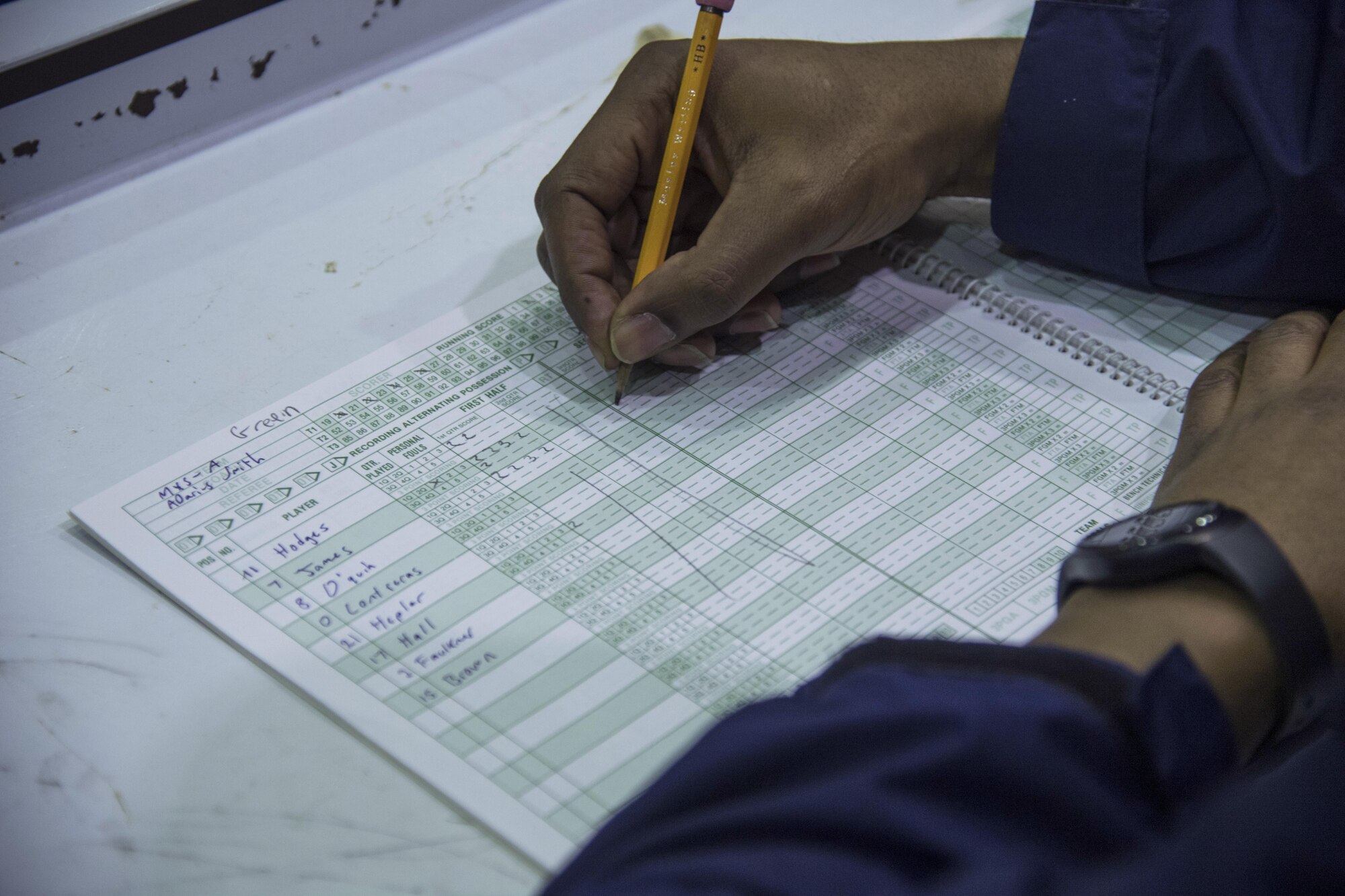Antwon Nixon, 374th Force Support Squadron, writes in the stats book after Neiman O’quin, 374th Maintenance Squadron, scores in the second half of the intramural basketball game at Yokota Air Base, Japan, Jan. 24, 2017. The stats book is used to keep track of player’s fouls, points scored and timeouts used. (U.S. Air Force photo by Staff Sgt. David Owsianka)