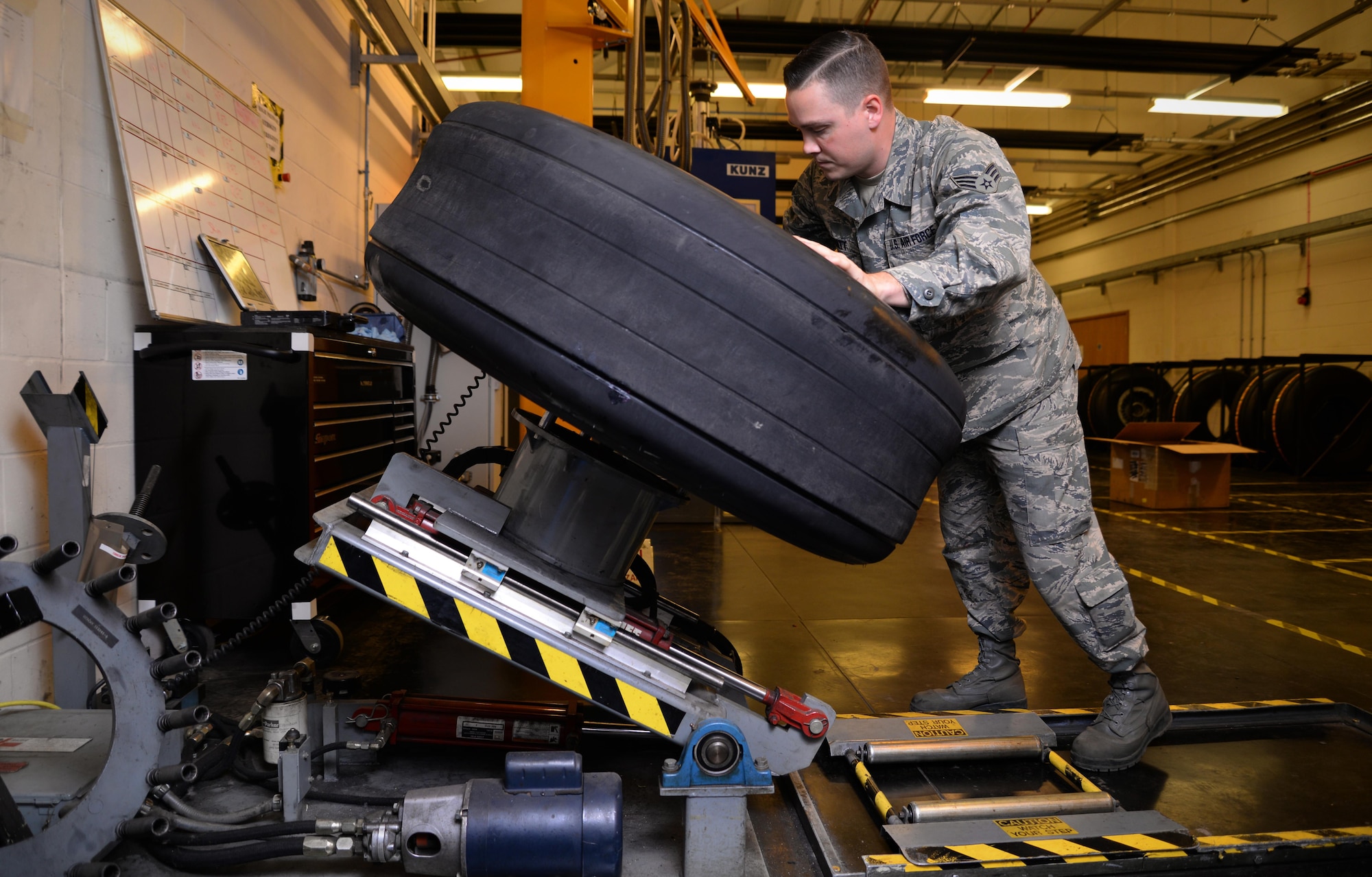 U.S. Air Force Senior Airman Tyler Hyatt, 100th Maintenance Squadron aero repair journeyman, places a wheel and tire assembly onto a wheel clamp Jan. 20, 2017, on RAF Mildenhall, England. The wheel clamp ensure proper disassembly of the wheel and tire. (U.S. Air Force photo by Senior Airman Christine Halan)