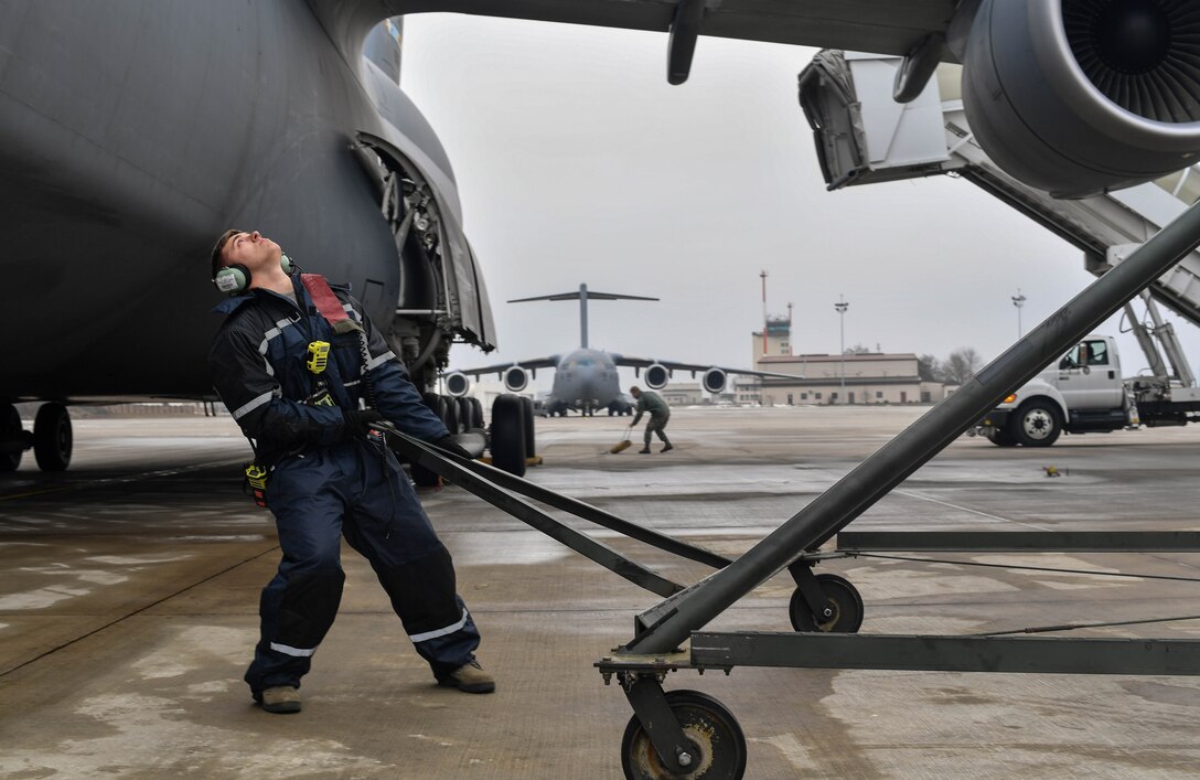 Staff Sgt. Zachary Rodewig, 721st Aircraft Maintenance Squadron C-5 Galaxy crew chief, pulls a maintenance platform up to a C-5 at Ramstein Air Base, Germany, Jan. 24, 2017. Rodewig and other 721st AMXS Airmen marshalled the plane to its spot, chocked the wheels, plugged it into a generator, checked tire pressure, refilled oil, and refueled the plane. The 721st AMXS inspects, repairs, and services all C-17 Globemaster III and C-5 aircraft that come through Ramstein. (U.S. Air Force photo by Senior Airman Tryphena Mayhugh)