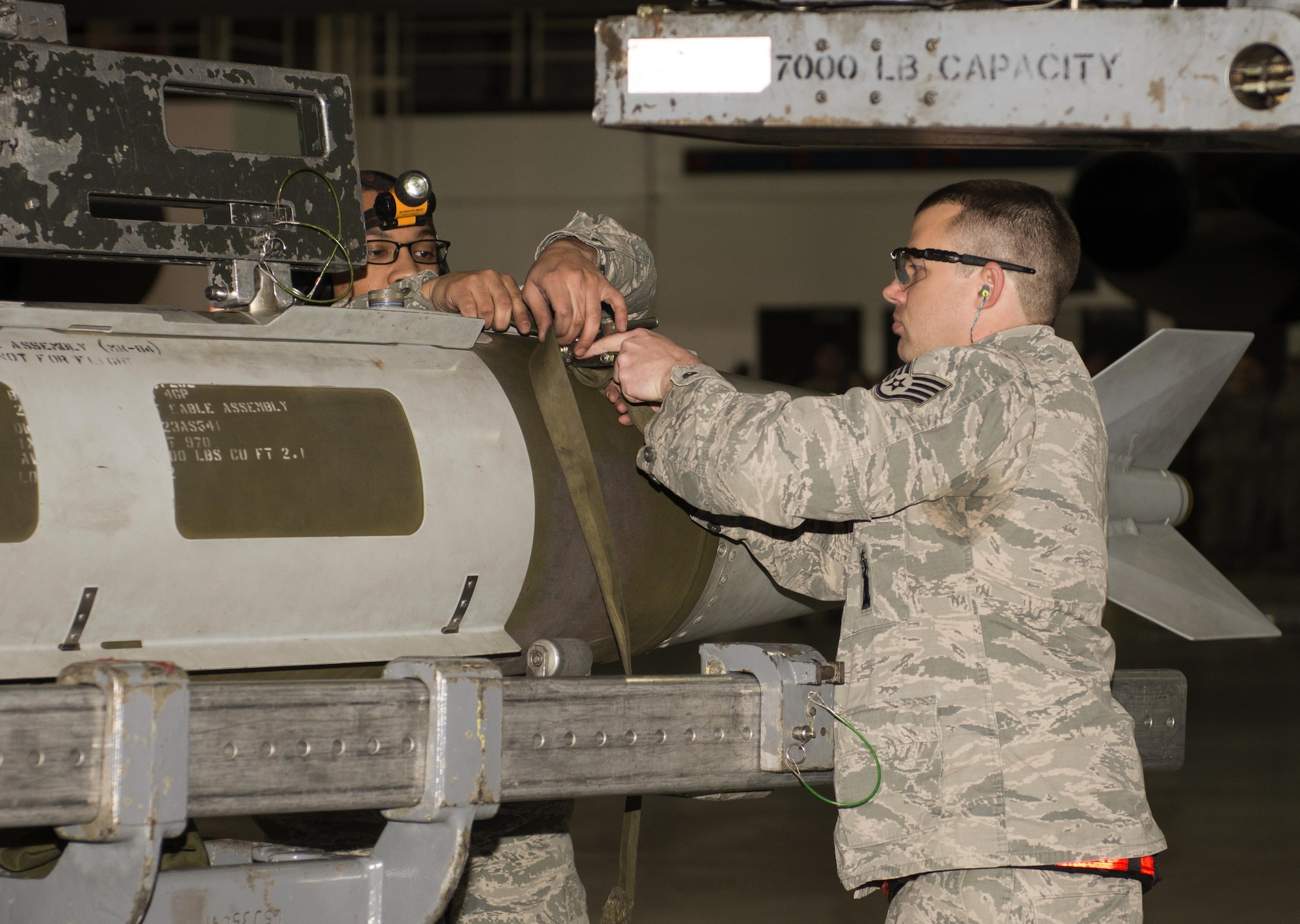 Staff Sgt. Eric Hathaway, 69th Aircraft Maintenance Unit weapons load crew chief, and Senior Airman Philip Johnson, 69th AMU weapons load crew member, strap an inert munition in place during the 5th Bomb Wing Load Crew of the Quarter competition in Dock 7 at Minot Air Force Base, N.D., Jan. 20, 2017. Hathaway and Johnson, assigned to the 5th Aircraft Maintenance Squadron, represented the 69th Air Maintenance Unit during the competition. (U.S. Air Force photo/Airman 1st Class Alyssa M. Akers)