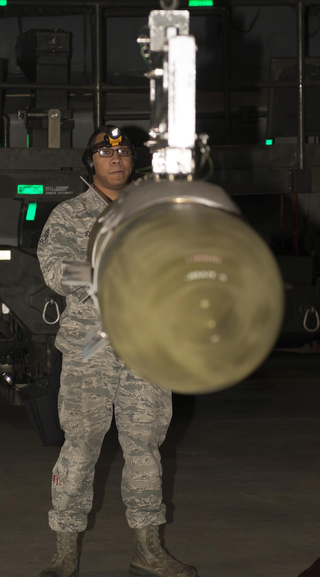 Senior Airman Philip Johnson, 69th Aircraft Maintenance Unit weapons load crew member, helps position an inert munition onto another machine during the 5th Bomb Wing Load Crew of the Quarter competition in Dock 7 at Minot Air Force Base, N.D., Jan. 20, 2017. Load crew members must maintain proficiency in 17 different types of munitions. (U.S. Air Force photo/Airman 1st Class Alyssa M. Akers)