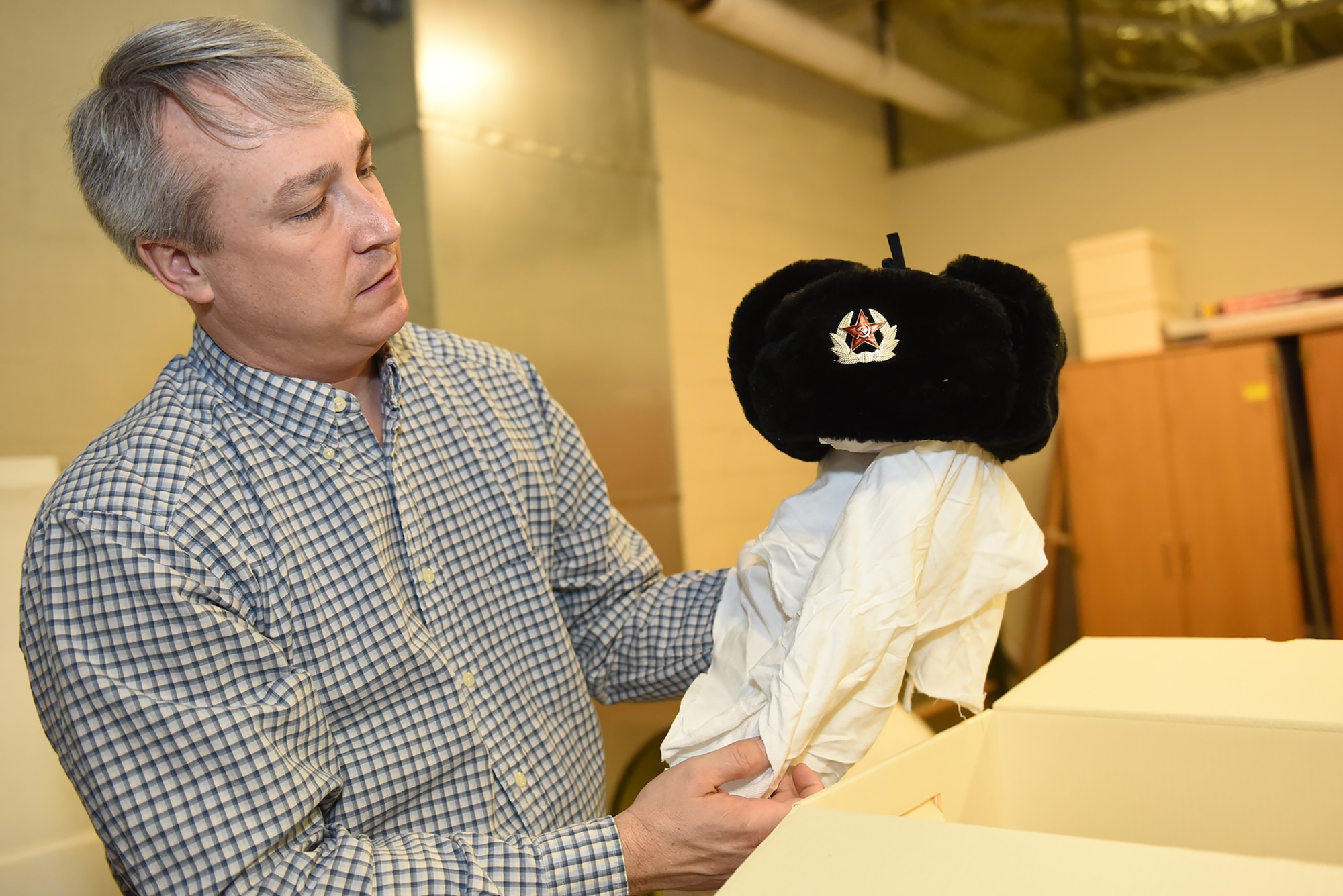 Rob Turnbow, the Malmstrom Historic Exhibit and Air Park curator, takes inventory of a Soviet-Army issued winter hat from the Cold War Jan. 26, 2017 at Malmstrom Air Force Base, Mont.  The museum contains more than 400 items on display that depicts the history of Malmstrom Air Force Base and the Minuteman program.  (U.S. Air Force photo/Jason Heavner)