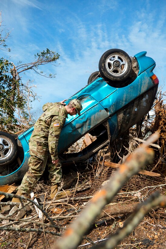 A National Guard soldier searches through an overturned vehicle while assisting with disaster relief efforts in Hattiesburg, Miss., Jan. 26, 2017, after a tornado swept through the area. Army National Guard photo by Staff Sgt. Tim Morgan
