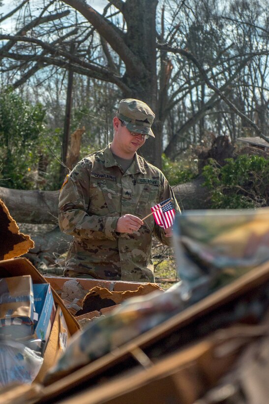 Army Sgt. Cowler looks at a flag he found while searching through debris in Hattiesburg, Miss., Jan. 26, 2017, in the aftermath of a tornado. Cowler is assigned to the Mississippi Army National Guard’s 3656th Maintenance Company, 184th Sustainment Command. Army National Guard photo by Staff Sgt. Tim Morgan