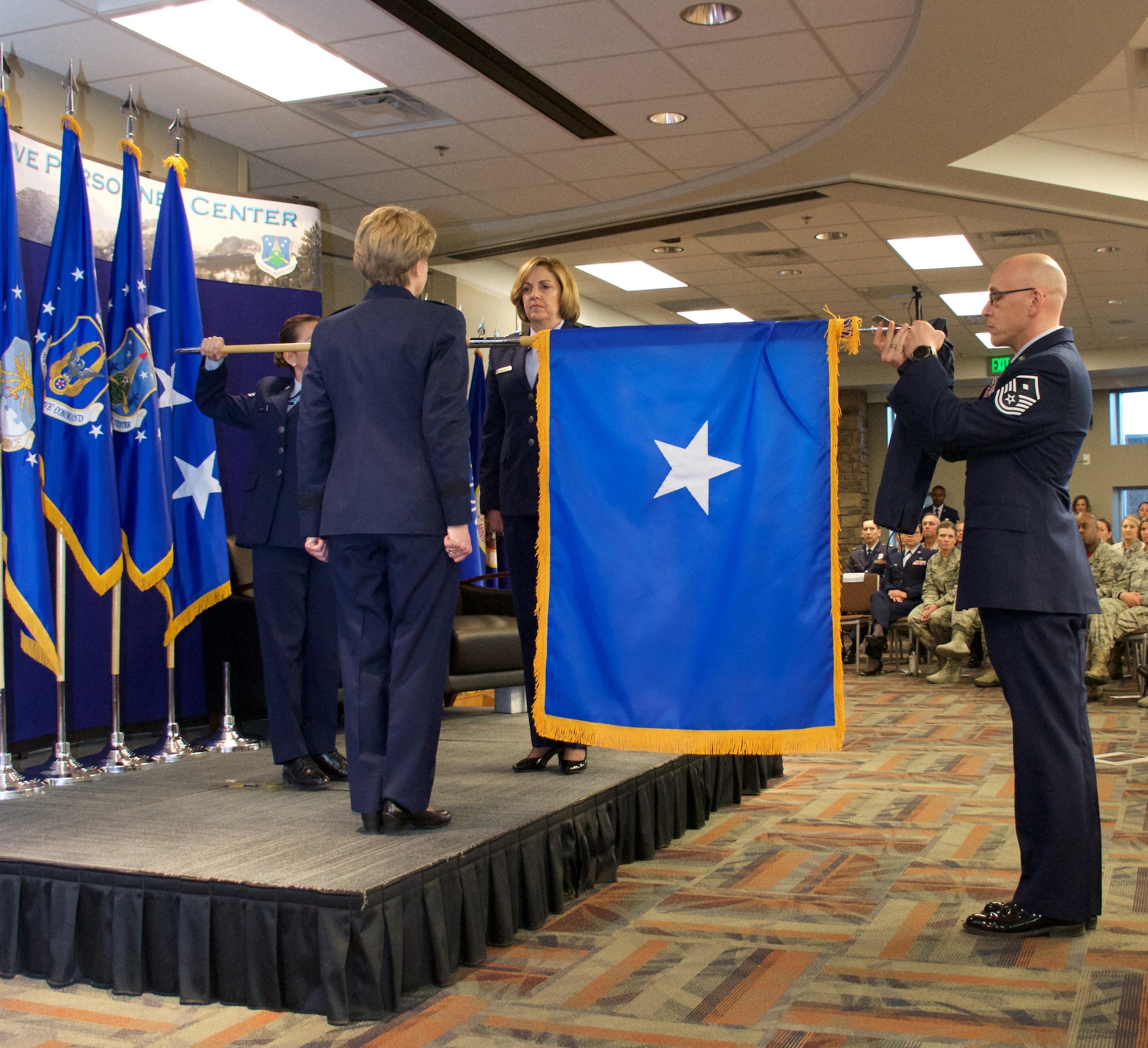 Brig. Gen. Ellen Moore (center), Commander, Air Reserve Personnel Center, stands at attention while her one star flag is unfurled by Senior Amn. Minette Ramirez (left) and Master Sgt. Jessie Thomas (right), and Lt. Gen. Maryanne Miller, Chief of Air Force Reserve and Commander, Air Force Reserve Command, looks on. The presentation was part of Moore's promotion ceremony Jan. 27, 2017, at Buckley Air Force Base, Colo. Moore is the first female brigadier general to command ARPC.  (U.S. Air Force photo by Master Sgt. Rick Grybos)